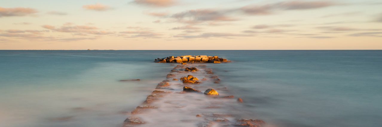 Coastal breakwater overflow with water high tide sunset