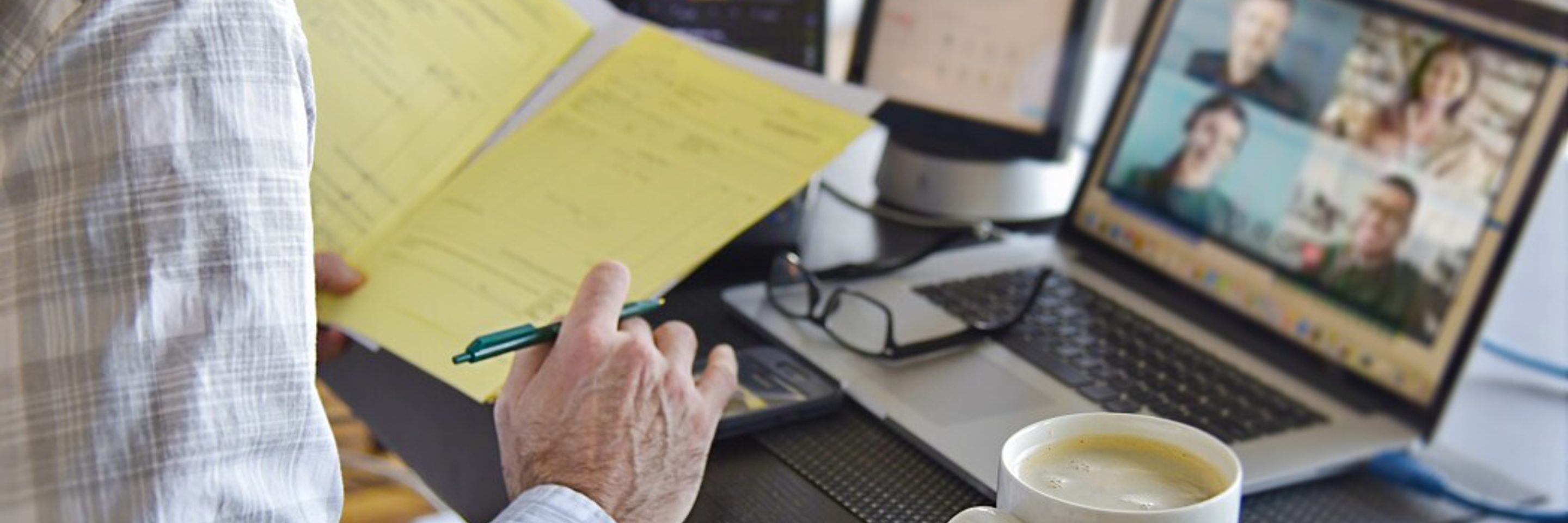 Man working from home signing contract documents while in a virtual video chat meeting on computer t20 O0 RK6b